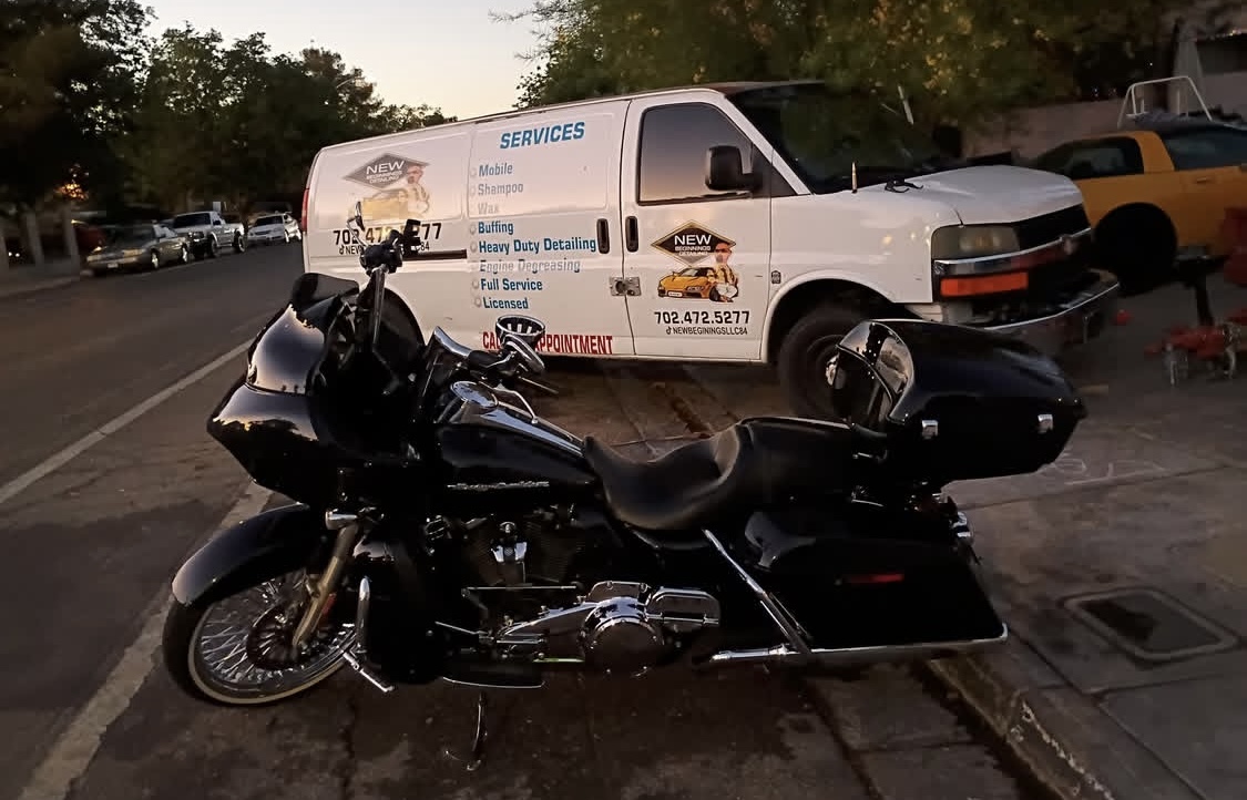 Black Harley-Davidson touring motorcycle in front of the branded detailing van at dusk